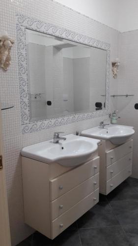 a bathroom with two sinks and a large mirror at La stanza del paradiso in Torre Pali 
