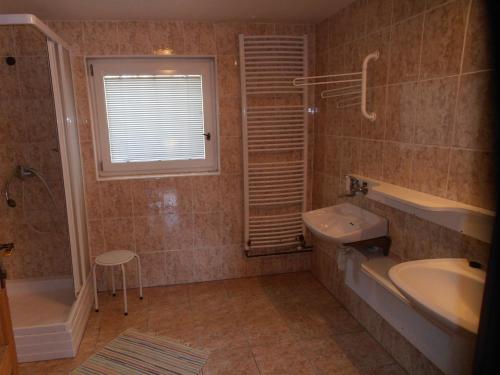 a bathroom with a sink and a tub and a toilet and a window at Penzion Samota in Louka