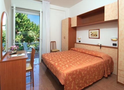 Habitación de hotel con cama, escritorio y ventana en Hotel Garden, en Bellaria-Igea Marina