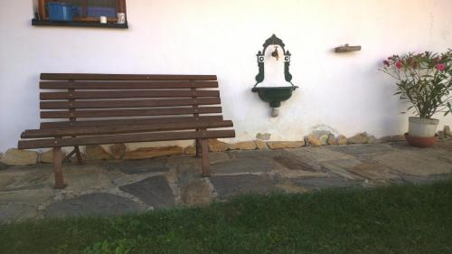 a wooden bench sitting next to a wall with a light at Chalupa u studny in Lukov