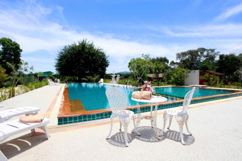 a table and chairs next to a swimming pool at Saree Lagoon Villa Koh Samui in Lipa Noi