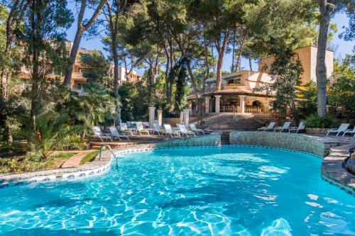 a swimming pool with chairs in front of a house at Lago Garden Apart-Suites & Spa Hotel in Cala Ratjada