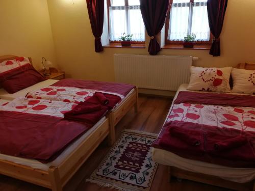 dwa łóżka w pokoju z oknami w obiekcie Vitis Vendégház w mieście Becsehely