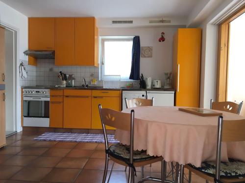 een keuken met oranje kasten en een tafel met stoelen bij Casa Fiorella in Locarno