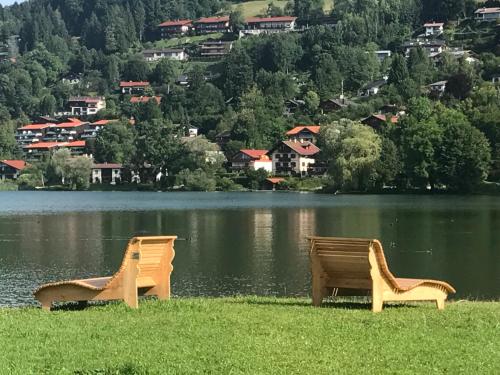 two chairs sitting on the grass near a lake at Lea am See - Bio Design Appartement in Tegernsee