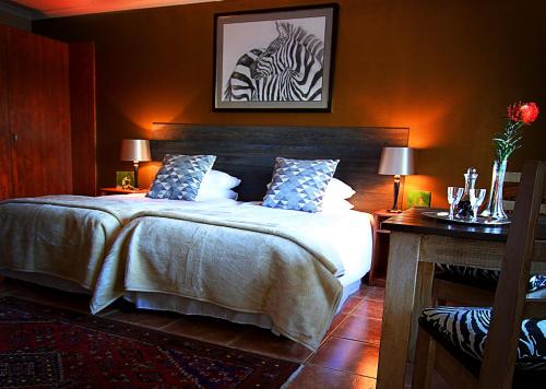a bedroom with a bed with a zebra picture on the wall at Golf and Garden Guesthouse in Somerset West