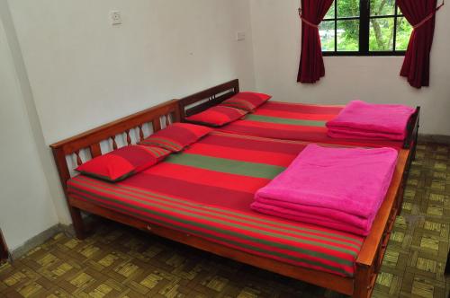 a bed with red pillows and pink blankets on it at Akiko Rest in Nuwara Eliya
