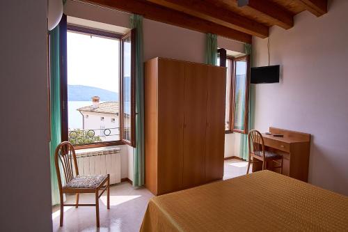 a room with a bed and a desk and a window at Hotel Tiziana Garnì in Gargnano
