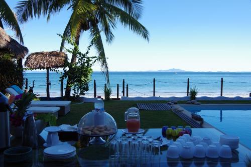 MadirokelyVilla Valiha Boutique Hotel的桌子,玻璃杯和一碗食物,在海边