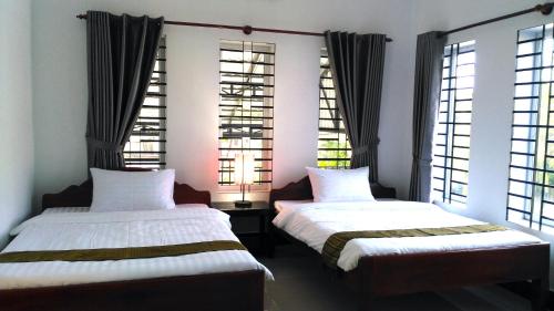 two beds in a room with windows at Anou Home - Guesthouse in Siem Reap
