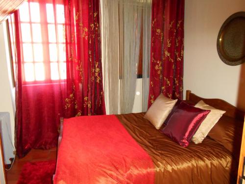 a bedroom with a bed with red curtains and a window at Coreto Apartments in Sabugueiro