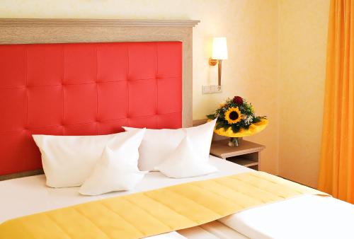 a bedroom with a red headboard and a bed with pillows at Hotel Wittelsbacher Höh in Würzburg