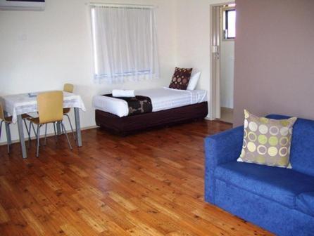- un salon avec un canapé bleu et une table dans l'établissement Fraser Coast Top Tourist Park, à Hervey Bay