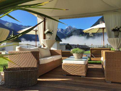 a patio with wicker furniture and a view of mountains at Hotel Alpenblick Zillertal in Hippach