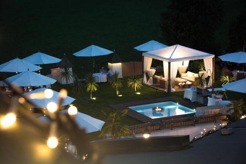 a pool with a gazebo and umbrellas at night at Romantik Hotel Alpenblick Ferienschlössl in Hippach