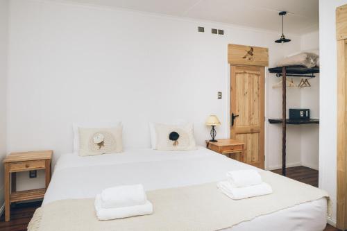 1 dormitorio con 1 cama blanca grande y toallas. en Hotel Estancia El Ovejero Patagónico, en Cerro Castillo