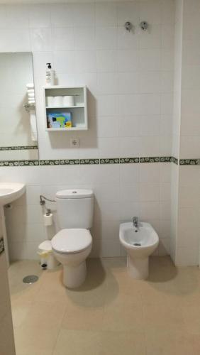 a white bathroom with a toilet and a sink at Apartamentos Centro 1 El Puerto de Santa Maria in El Puerto de Santa María