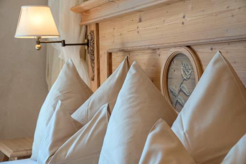 a pile of pillows on a bed with a lamp at Hotel Alpenblick Zillertal in Hippach