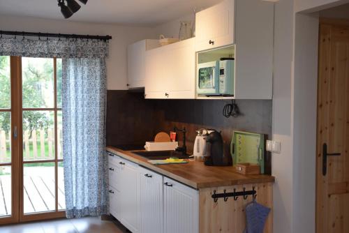 a kitchen with white cabinets and a window at Apartmány Kojákovice - Třeboň in Jílovice