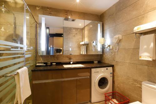 La salle de bains est pourvue d'un lave-linge et d'un miroir. dans l'établissement Boman Holiday Apartment Bei Jing lu Jie Deng Du Hui Branch, à Canton