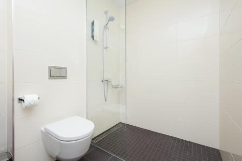 a bathroom with a toilet and a glass shower at 8ERA Business Executive Rotermanni Apartments in Tallinn