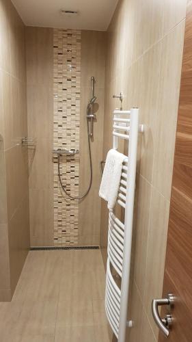 a bathroom with a shower and towels on a rack at Tündérlak Vendégház in Balatonfüred