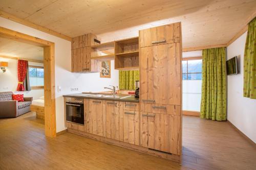 een keuken met houten kasten en een woonkamer bij Naturdorf Oberkühnreit in Neukirchen am Großvenediger