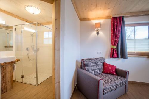 a bathroom with a shower and a chair at Naturdorf Oberkühnreit in Neukirchen am Großvenediger