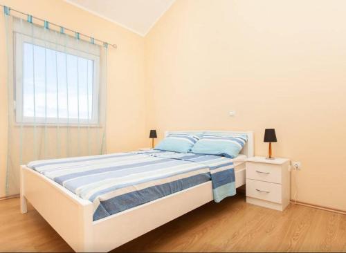 a white bedroom with a bed and a window at Duplex Peroj Istrie in Peroj