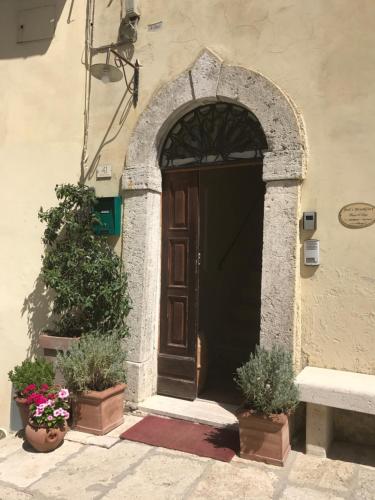 uma entrada para um edifício com uma porta e vasos de plantas em BBBagni em Bagni San Filippo