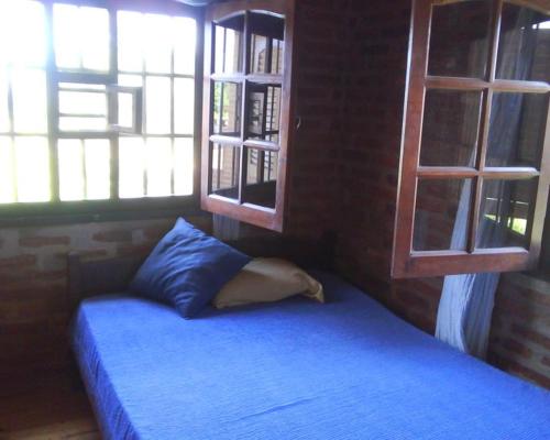 a bedroom with a blue bed with two windows at Angeluz Paso De La Patria in Paso de la Patria