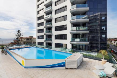 a swimming pool in front of a building at Ocean Eleven 5 in Mount Maunganui