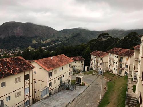 un groupe de bâtiments avec des montagnes en arrière-plan dans l'établissement Apartamento com vista espetacular, à Nova Friburgo
