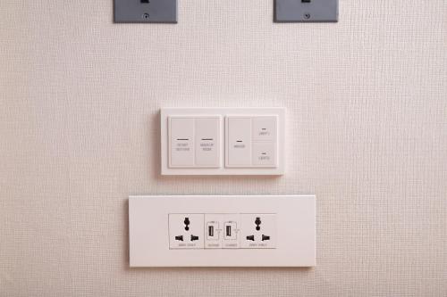 a white lightswitch on a wall with three lights at Seogwipo KAL Hotel in Seogwipo