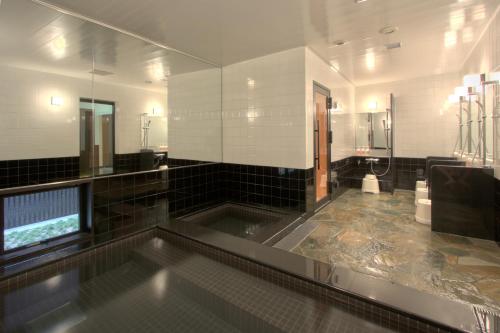 un ampio bagno con vasca al centro di Green Rich Hotel Hamada Ekimae (Artificial hot spring Futamata Yunohana) a Hamada