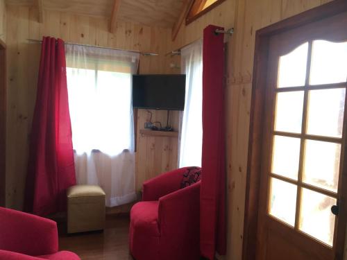 a living room with two red chairs and a window at Cabañas Los Canelos Pucon, Hermosa Granja de 20 hectaréas a orillas del Río Liucura in Pucón