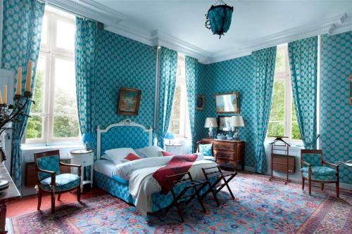 sypialnia z łóżkiem w pokoju z niebieską tapetą w obiekcie Chateau de Raissac w Béziers