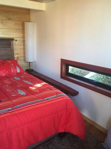 a bedroom with a red bed and a window at Cabañas Ayalén con vista al Lago in Pucón
