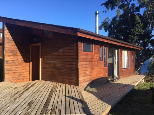 a small wooden cabin with a large wooden deck at Cabañas Ayalén con vista al Lago in Pucón