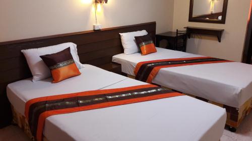 two beds in a hotel room with orange pillows at Lanna Thai Guesthouse in Chiang Mai