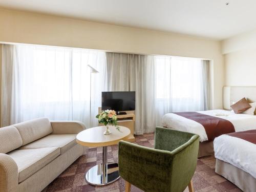 a hotel room with a couch and a bed at City Plaza Osaka in Osaka