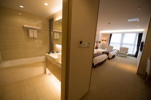 a hotel room with a bed and a tub and a bathroom at Suzhou Sun Plaza Hotel in Suzhou