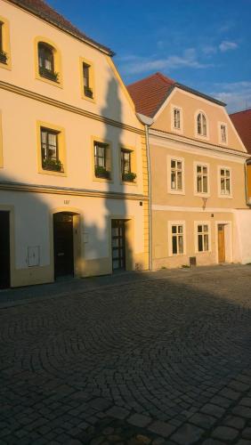 a large white building next to a brick street at Apartmany Žatec in Žatec