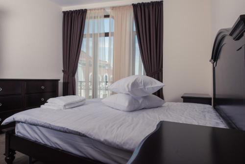 a bedroom with a bed with pillows and a window at Old City - Apartments in Constanţa