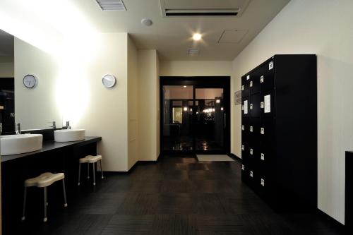 a bathroom with two sinks and two counters with stools at Green Rich Hotel Iwakuni Ekimae (Artificial hot spring Futamata Yunohana) in Iwakuni