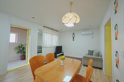 a living room with a wooden table and chairs at Namhae Frankfurt Pension in Namhae