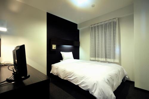 a bedroom with a bed and a flat screen tv at Green Rich Hotel Iwakuni Ekimae (Artificial hot spring Futamata Yunohana) in Iwakuni