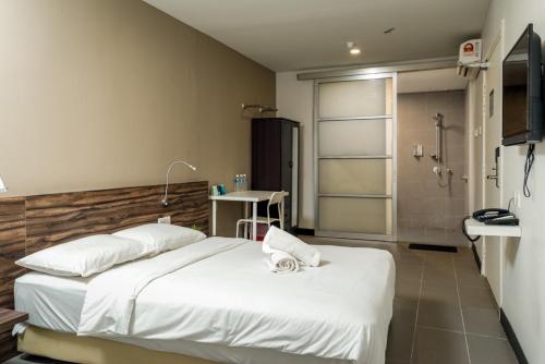 um quarto com uma grande cama branca e um chuveiro em MAX Hotel Subang Jaya em Subang Jaya
