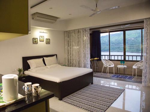 a bedroom with a bed and a room with a balcony at Lavasa Luxury Lakeview Studio in Lavasa