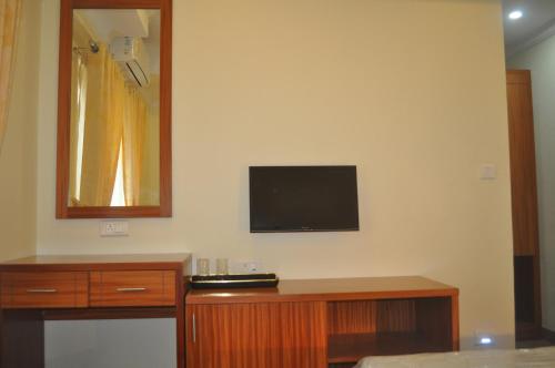 a room with a tv on a wall with a wooden desk at Vettoor Nanas Inn in Ettumānūr